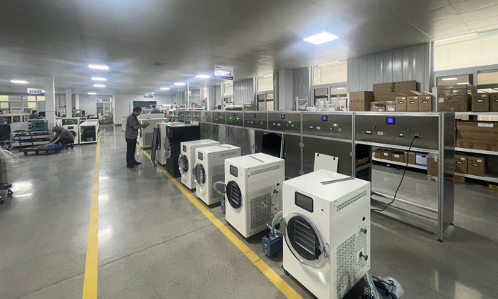 Geliss freeze dryer factory facility history in 2025 - modern large scale manufacturing workshop with streamlined assembly lines and wooden shipping crates for wholesale orders